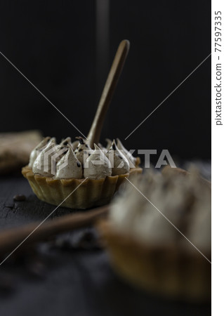 Cappuccino tart with cinnamon sticks and coffee beans on rustic wooden table 77597335