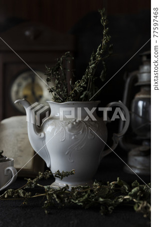 Tea Party. Cup of tea and Teapot on wooden table with old clock and book in Background Tea Party. Cup of tea and Teapot on wooden table with old clock and book in Background 77597468