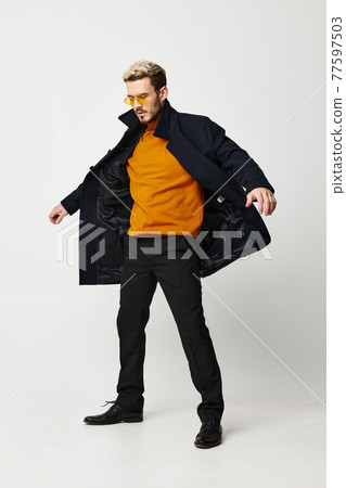man in unbuttoned coat orange sweater pants and boots man in unbuttoned coat orange sweater pants and boots 77597503