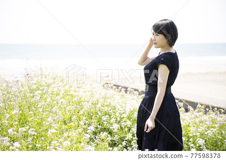 A young woman looking out at the sea and a flower garden (Yuigahama, Kamakura City, Kanagawa Prefecture) 77598378