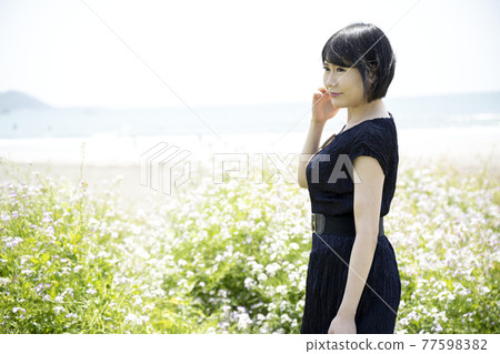 A young woman looking out at the sea and a flower garden (Yuigahama, Kamakura City, Kanagawa Prefecture) 77598382