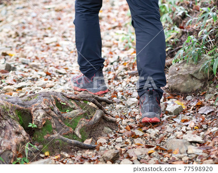 A man climbing a mountain wearing trekking shoes A man climbing a mountain wearing trekking shoes 77598920