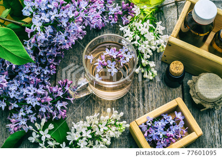 Essential oil and a cup of tea made from lilac flowers Essential oil and a cup of tea made from lilac flowers 77601095