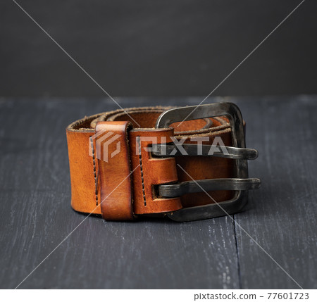 brown leather men's belt with metal buckle on a wooden background 77601723