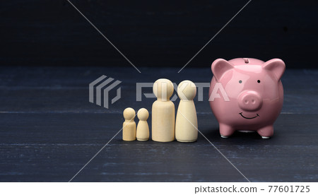 wooden family figurines and pink ceramic piggy bank, savings concept, budget control wooden family figurines and pink ceramic piggy bank, savings concept, budget control 77601725