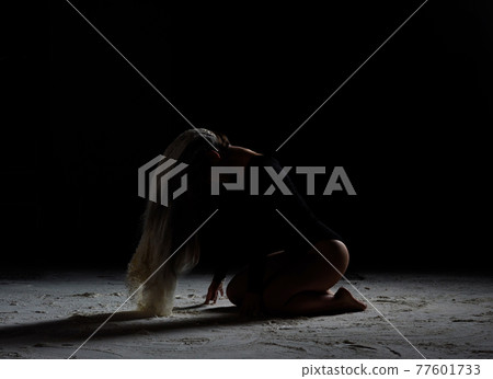 beautiful young woman of Caucasian appearance sits with her head down, long hair in flour 77601733