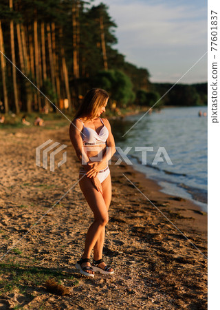 Caucasian fit woman with sport body is posing on beach at sunset time. 77601837