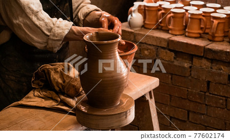 Potter hands making in clay on pottery wheel. Authentic pottery workshop 77602174