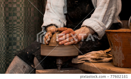 Potter hands making in clay on pottery wheel. Authentic pottery workshop 77602181