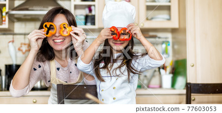 Mother and daughter cooking at the kitchen 77603053