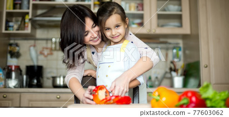 Mother and daughter cooking at the kitchen Mother and daughter cooking at the kitchen 77603062