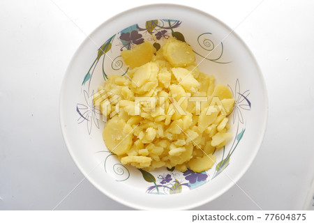 Close up of slice of raw potato in a bowl Close up of slice of raw potato in a bowl 77604875