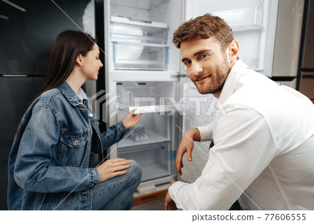 Young couple selecting new refrigerator in household appliance store Young couple selecting new refrigerator in household appliance store 77606555
