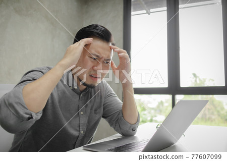 Serious face of man working on laptop alone in the room. Serious face of man working on laptop alone in the room. 77607099