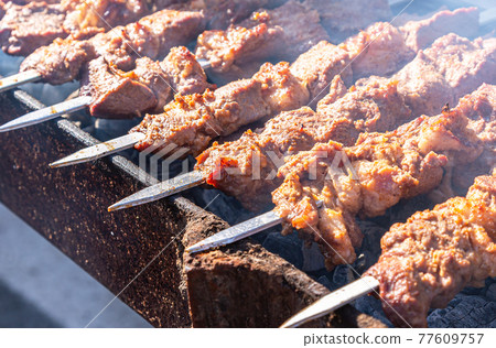 Grilled appetizing kebab cooking on metal skewers. Selective focus 77609757