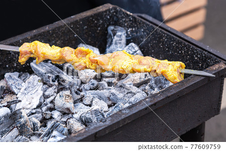 Grilled appetizing kebab cooking on metal skewer Grilled appetizing kebab cooking on metal skewer 77609759