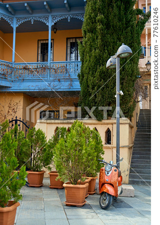 The architecture of the old district of Tbilisi. A retro moped is parked in front of a stylish old building The architecture of the old district of Tbilisi. A retro moped is parked in front of a stylish old building 77610246