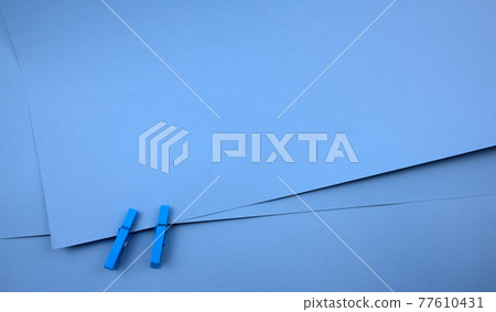 Elegant blue cerulean layer papers texture abstract background binding with wooden blue craft pegs. Empty space for communication, message, image or design. Top view, horizontal. 77610431