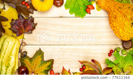 Halloween Pumpkins. Natural harvest with orange pumpkin, fall dried leaves, red berries and acorns, chestnuts on wooden background in shape frame. Creative Top view flat lay autumn composition. 77611168