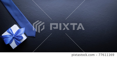 Gift father day. Blue bowtie or tie, white box with bow ribbon on dark background. Happy loving family and Fathers Day concept. 77611169