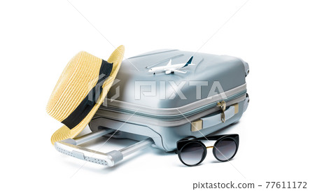 Tropical background. Suitcase, sunglasses with toy plane and straw hat in travel composition isolated on white background. Exotic tropical beach with copy space. Tropical background. Suitcase, sunglasses with toy plane and straw hat in travel composition isolated on white background. Exotic tropical beach with copy space. 77611172