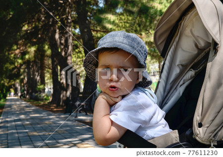 Emotionally dissatisfied indignant child in a stroller. 77611230