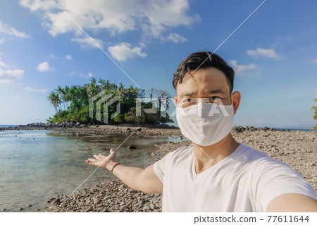Man with face mask has a summer sea trip while in Covid-19 pandemic. Man with face mask has a summer sea trip while in Covid-19 pandemic. 77611644