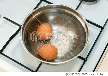 Closeup of three eggs boiling in pot of hot water Closeup of three eggs boiling in pot of hot water 77611679