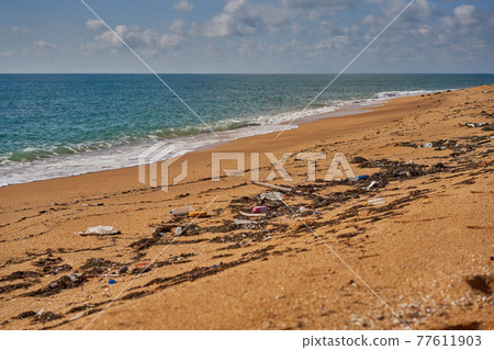 Poured trash on the beach - empty used dirty plastic bottles, packages and other household rubbish. Poured trash on the beach - empty used dirty plastic bottles, packages and other household rubbish. 77611903
