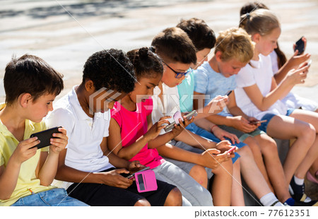 Children are playing on smartphone in the playground Children are playing on smartphone in the playground 77612351