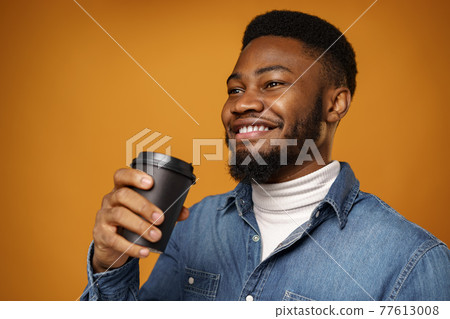 Young african american guy enjoying his takeaway cup of coffee against yellow background Young african american guy enjoying his takeaway cup of coffee against yellow background 77613008