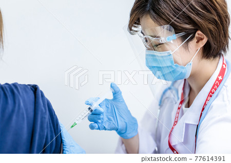 Female doctor injecting coronavirus vaccine 77614391