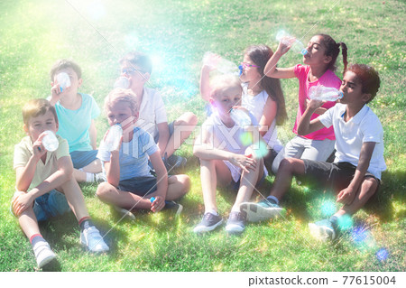 Happy children drinking water after running in park outdoors Happy children drinking water after running in park outdoors 77615004
