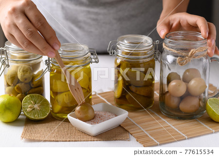 Homemade various pickled fruit in a glass jar with hand Homemade various pickled fruit in a glass jar with hand 77615534
