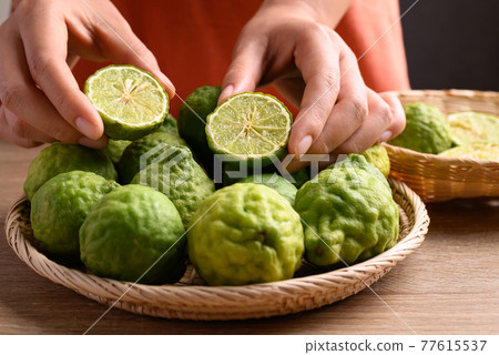Fresh bergamot fruit in a basket holding by woman hand Fresh bergamot fruit in a basket holding by woman hand 77615537