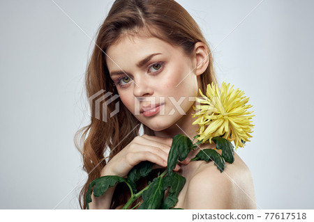 Portrait of a beautiful woman with a yellow flower on a light background cropped with Copy Space Model 77617518