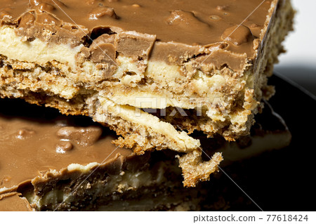 Slice of Swedish almond and chocolate cake with filling and nuts 77618424