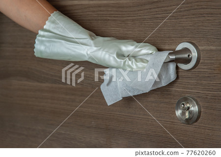 Actions to prevent the spread of coronavirus COVID-19, Disinfection of the door handle. Hand in white gloves wipes the door handle with a disinfectant. 77620260