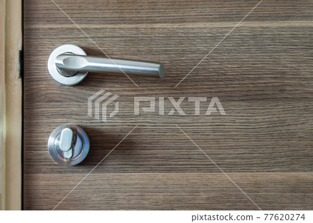 Detail of a Door knob or handle and keyhole made of Stainless on the wooden door horizontal. Detail of a Door knob or handle and keyhole made of Stainless on the wooden door horizontal. 77620274