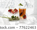 Cup of tea and wild strawberries on a white lace background 77622463