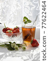 Cup of tea and wild strawberries on a white lace background 77622464