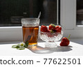 Cup of tea and wild strawberries on a white background 77622501
