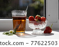 Cup of tea and wild strawberries on a white background 77622503
