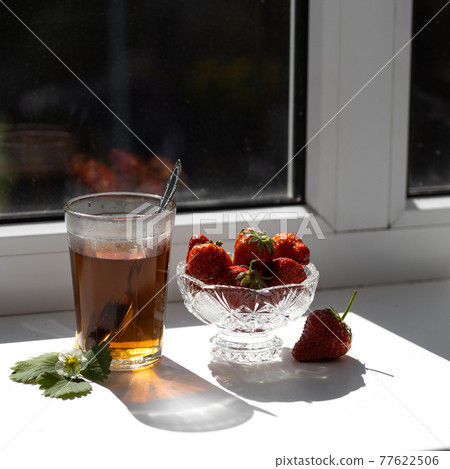 Cup of tea and wild strawberries on a wooden background 77622506