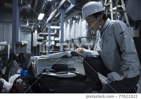 男工在檢查工廠前檢查圖紙 77622822