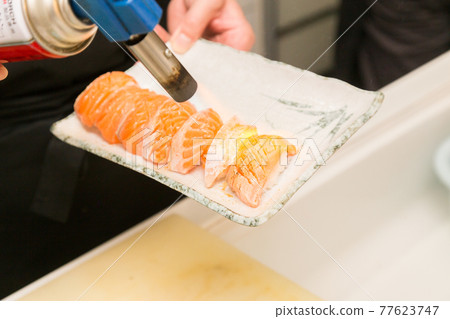 Hands of a craftsman who roasts salmon Hands of a craftsman who roasts salmon 77623747