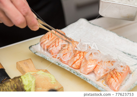 供應烤三文魚握壽司的工匠之手 77623753