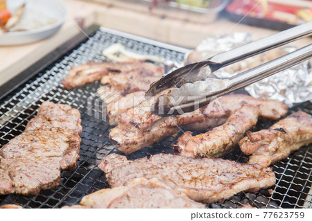 BBQ scene of lifting meat with tongs BBQ scene of lifting meat with tongs 77623759