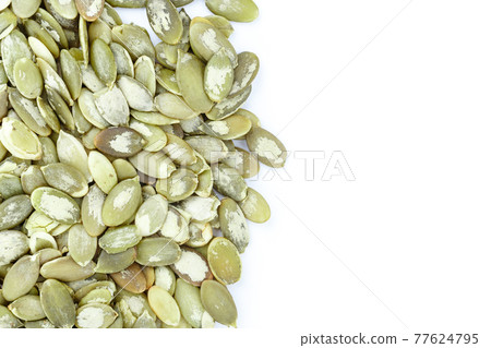 Close-up background texture of green pumpkin seeds on a white background. Space for text. Close-up background texture of green pumpkin seeds on a white background. Space for text. 77624795