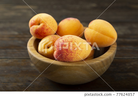 Fresh apricots in a wooden plate. Fresh apricots in a wooden plate. 77624857